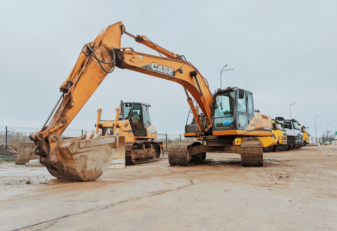 Gelbe Baumaschinen wie Bagger und Planierraupe auf einem Auktionsgelände.